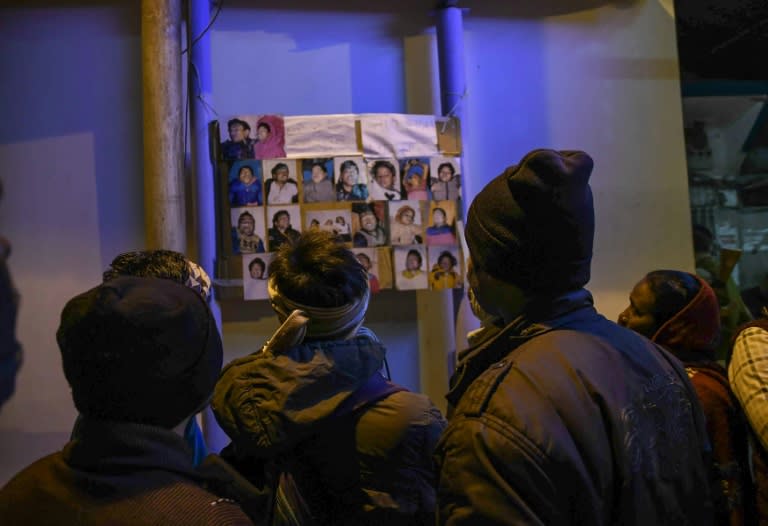 Relatives look at the images of people who drowned in a boat accident on the river Ganges near Patna, eastern India, on January 15, 2017