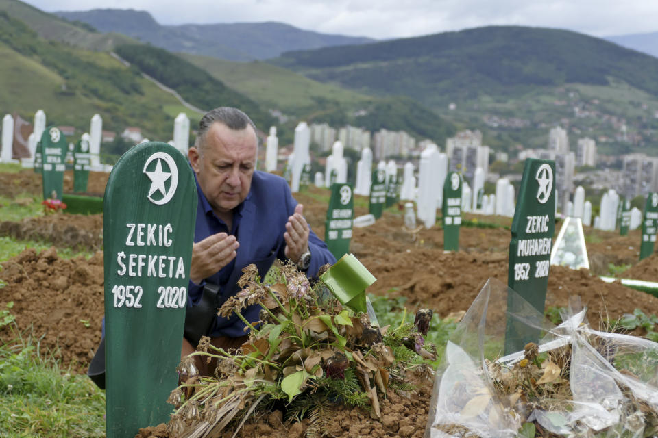 Tarik Svraka visits the graves of his parents in law who died of COVID-19 related complications, in Zenica, Bosnia, Monday, Sept. 28, 2020. The coronavirus skeptics and rebels in Bosnia grow louder in step with the rising number of infections in the country. Recently, several families who lost their loved ones to COVID-19 were confronted online, and some even in real life, by scores of random virus believers and deniers sifting through their pain and questioning their relatives’ cause of death. (AP Photo/Almir Alic)