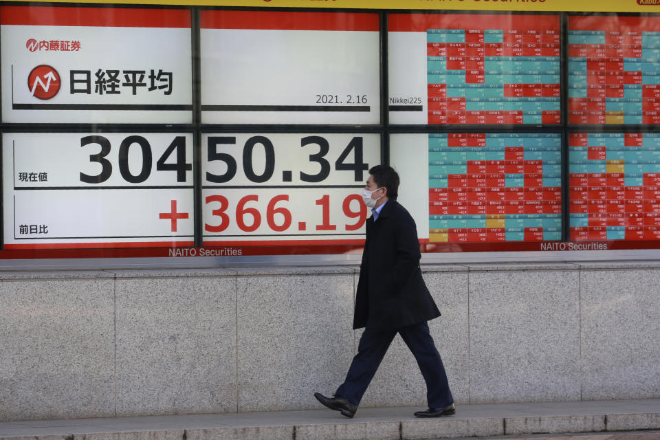 A man wearing a face mask walks by an electronic stock board of a securities firm in Tokyo, Tuesday, Feb. 16, 2021. Asian shares advanced on Tuesday, lifted by the economic recovery, vaccine rollouts and signs that new coronavirus cases may be abating. (AP Photo/Koji Sasahara)