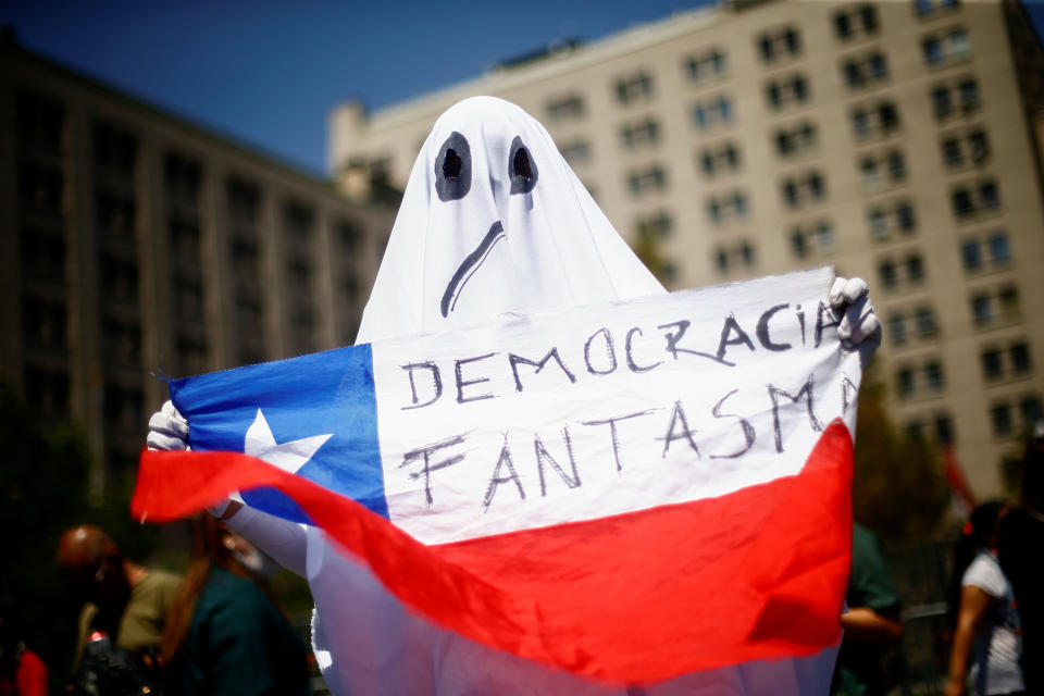 A demonstrator dressed as a ghost holds a Chilean flag with the legend "ghost democracy" during anti-government protests in Santiago, Chile. (Photo: Edgard Garrido / Reuters)