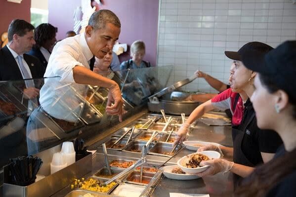 Obama reaching over the sneeze guard