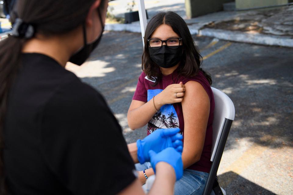 Audrey Romero, 16, rolls up their sleeve to receive a first dose of the Pfizer Covid-19 vaccine at a mobile vaccination clinic at the Weingart East Los Angeles YMCA on May 14, 2021 in Los Angeles, California. - The campaign to immunize America's 17 million adolescents aged 12-to-15 kicked off in full force on May 13. The YMCA of Metropolitan Los Angeles is working to overcome vaccine hesitancy and expand access in high risk communities with community vaccine clinics in the area. (Photo by Patrick T. FALLON / AFP) (Photo by PATRICK T. FALLON/AFP via Getty Images)