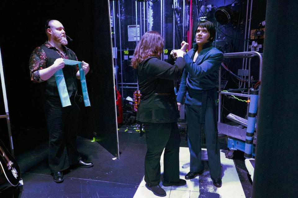 Austin VanBecelaere, left, a show technician and scenic carpenter, waits with a scarf as Mackenzie Goodwin, a stage manager, makes an adjustment before Trevino takes the stage for the show’s opening number.