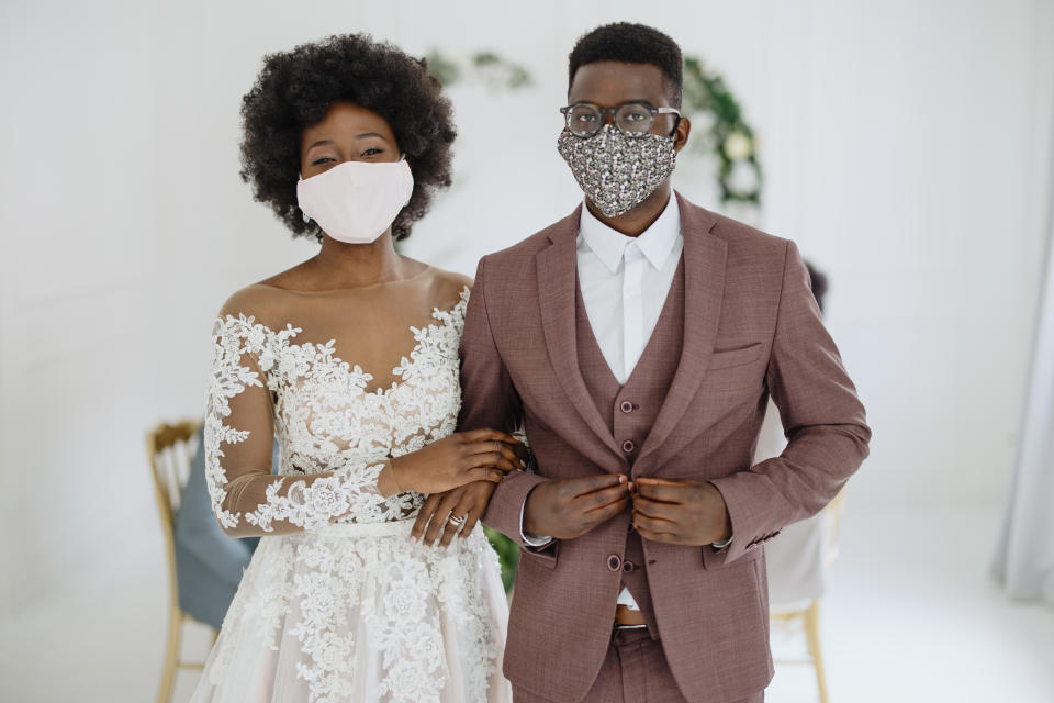 Young newlywed Black couple wears face protective masks at the reception of their wedding