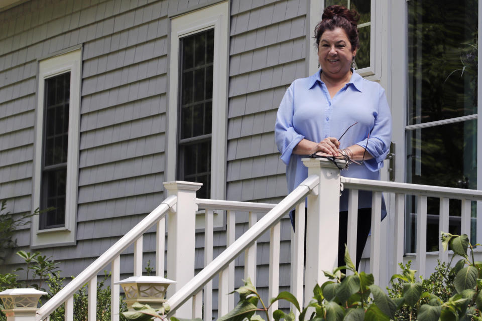 Poet Tammi Truax poses, Wednesday, July 29, 2020, on the front steps of her home in Eliot, Maine. Truax, the poet laureate for Portsmouth, N.H., pens a weekly pandemic poem that is included in the city's COVID-19 newsletter. (AP Photo/Charles Krupa)