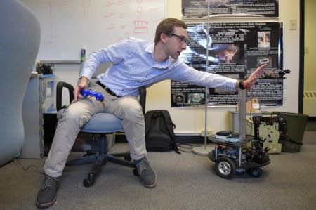 University of Colorado Boulder undergraduate researcher Bell checks the video feed while running an experiment for an assembly robot at a lab