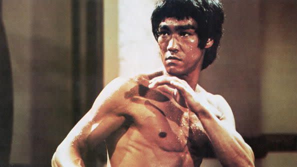 a shirtless bruce lee making a kung fu pose