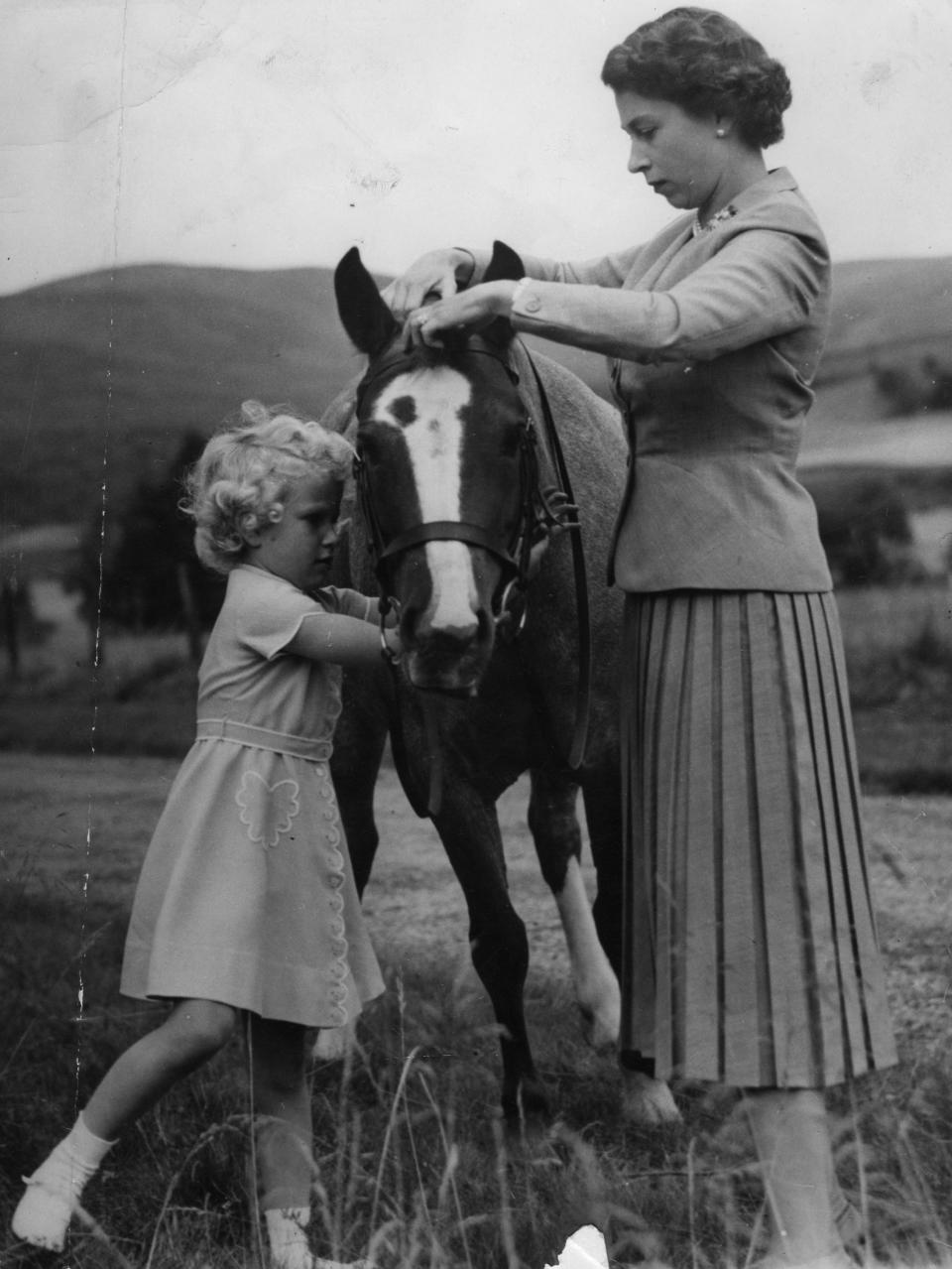 Princess Anne helps her mother, Queen Elizabeth II, fit the bridle to the pony 'Greensleeves', the the grounds of Balmoral Castle during the Royal family's summer holiday in Scotland.   (Photo by PA Images via Getty Images)
