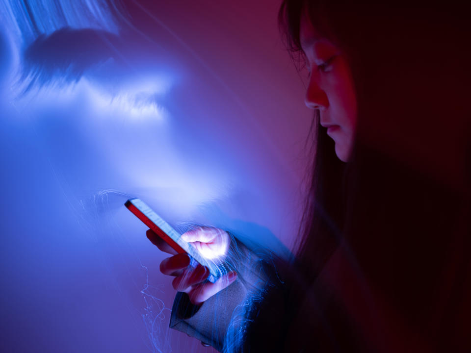 Young woman using a mobile phone set against a gradient purple and pink background.