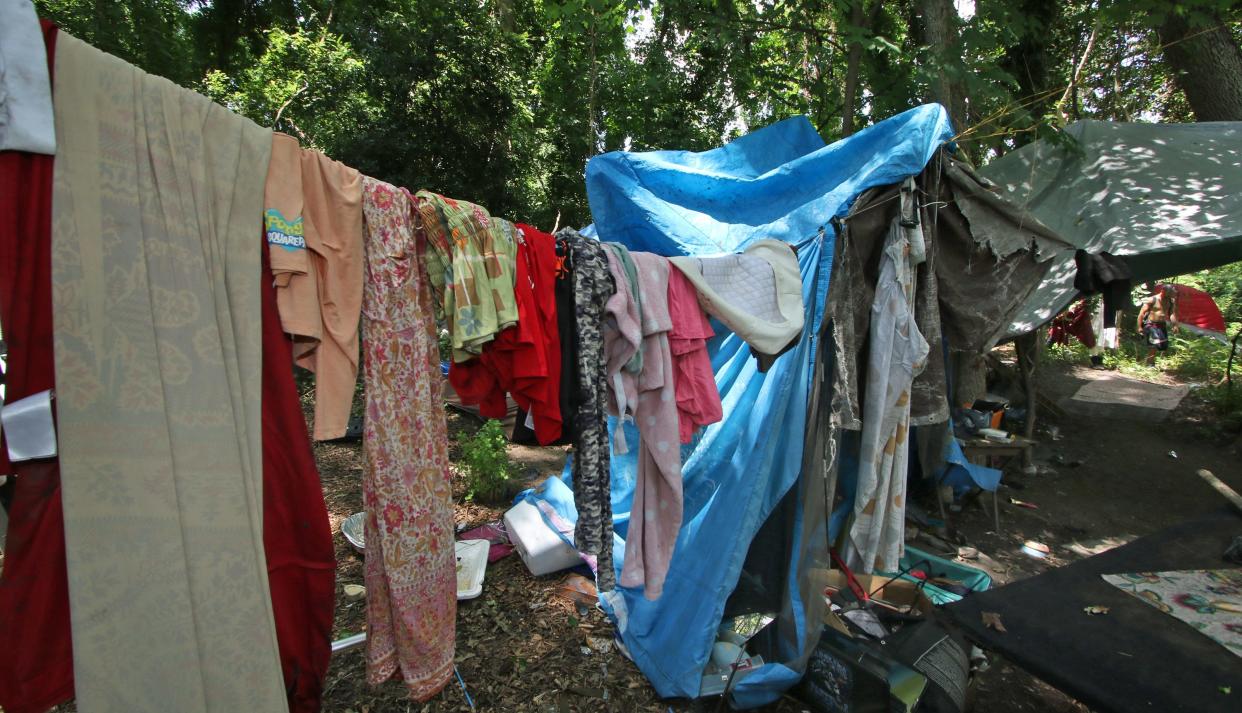Laundry hangs on a line to dry at a homeless encampment in the wooded area behind St. Paul Baptist Church on North Oakland Street Friday afternoon, July 29, 2022.