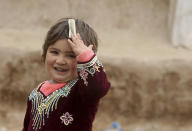 In this Thursday, Feb. 13, 2020 photo, an Afghan refugee girl holds a small banknote in the Kabobayan refugee camp, Peshawar, Pakistan. After 40 years, more than 1.5 million Afghan refugees still live in neighboring Pakistan. They feel abandoned by their own government, increasingly unwelcome in their reluctant host country and ignored by the United Nations. (AP Photo/Muhammad Sajjad)