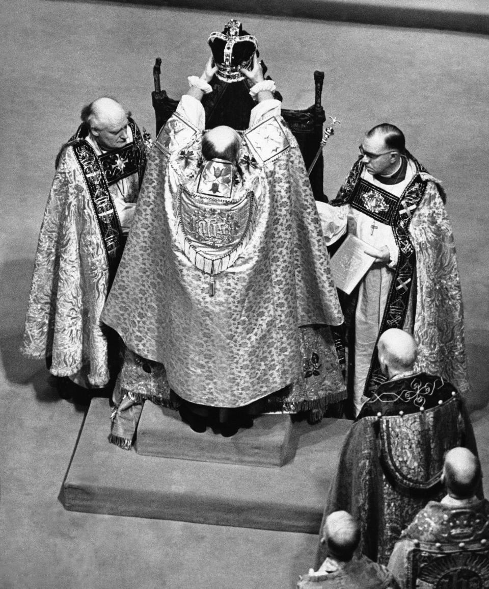 FILE - The Archbishop of Canterbury holds the ritual crown of England, the crown of St. Edward, over the head of Queen Elizabeth II, prior to the actual crowning at the coronation ceremony in Westminster Abbey, London, June 2, 1953. Britain is getting ready for a party featuring mounted troops, solemn prayers — and a pack of dancing mechanical corgis. The nation will celebrate Queen Elizabeth II’s 70 years on the throne this week with four days of pomp and pageantry in central London. (AP Photo/File)