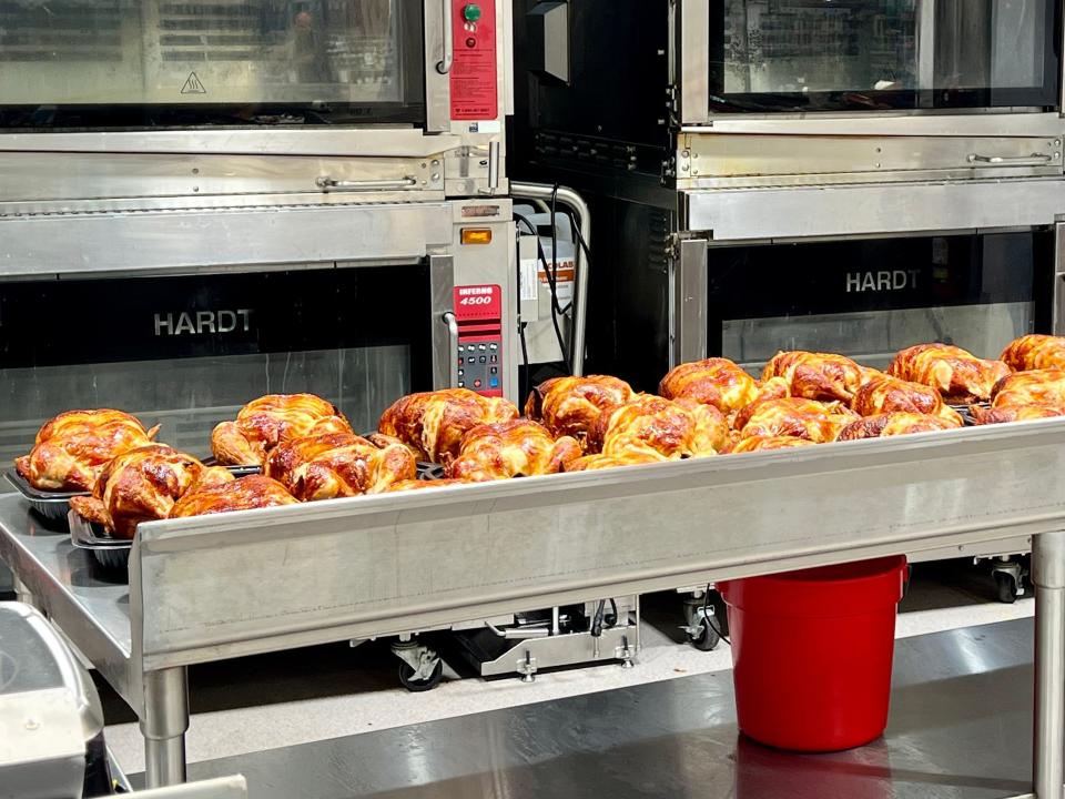 Several rotisserie chickens behind counter before being packaged at Costco