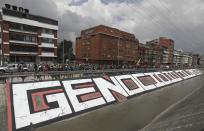 Indigenous people march past the Spanish word "Genocide" to protest the government in Bogota, Colombia, Monday, Oct. 19, 2020. The leaders of the indigenous communities say they are mobilizing to reject massacres, assassinations of social leaders, criminalization of social protest, to defend their territory, democracy and peace, and plan to stay in the capital for a nationwide protest and strike on Oct. 21. (AP Photo/Fernando Vergara)
