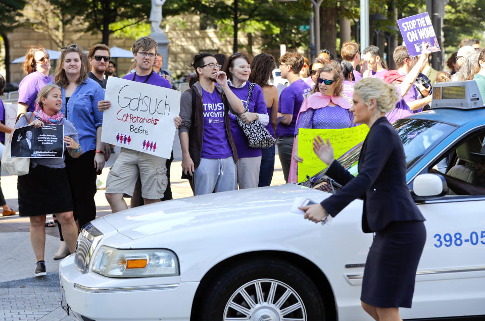 Hotel staff member helps direct vehicle traffic as demonstrators gather in front of the Trump Hotel in Washington, Thursday, Sept. 28, 2017. Supreme Court Justice Neil Gorsuch is scheduled to speak at a luncheon hosted by a conservative group at the Trump Hotel. (AP Photo/Pablo Martinez Monsivais)