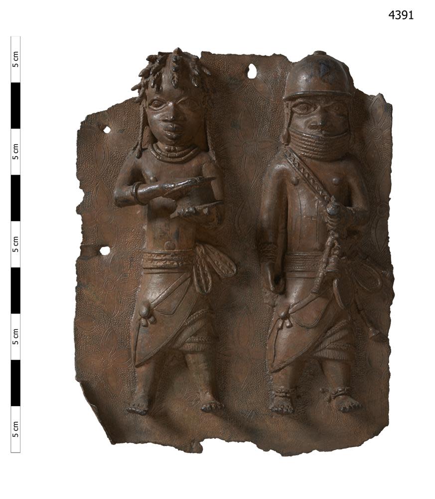 This handout photo provided by Horniman Museum and Gardens shows a brass plaque depicting a war chief and a royal military priest carrying a leather gift box. (Horniman Museum and Gardens via AP)