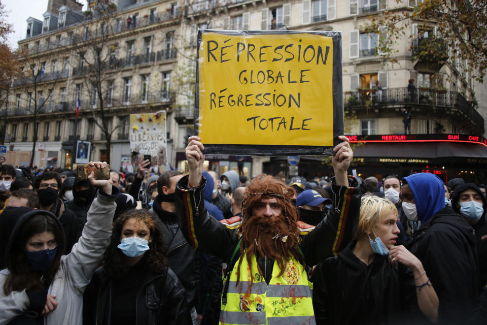 A protester holds a poster reading "Global repression, Total regression"" during a protest, Saturday, Dec.12, 2020 in Paris. Protests are planned in France against a proposed bill that could make it more difficult for witnesses to film police officers. (AP Photo/Thibault Camus)