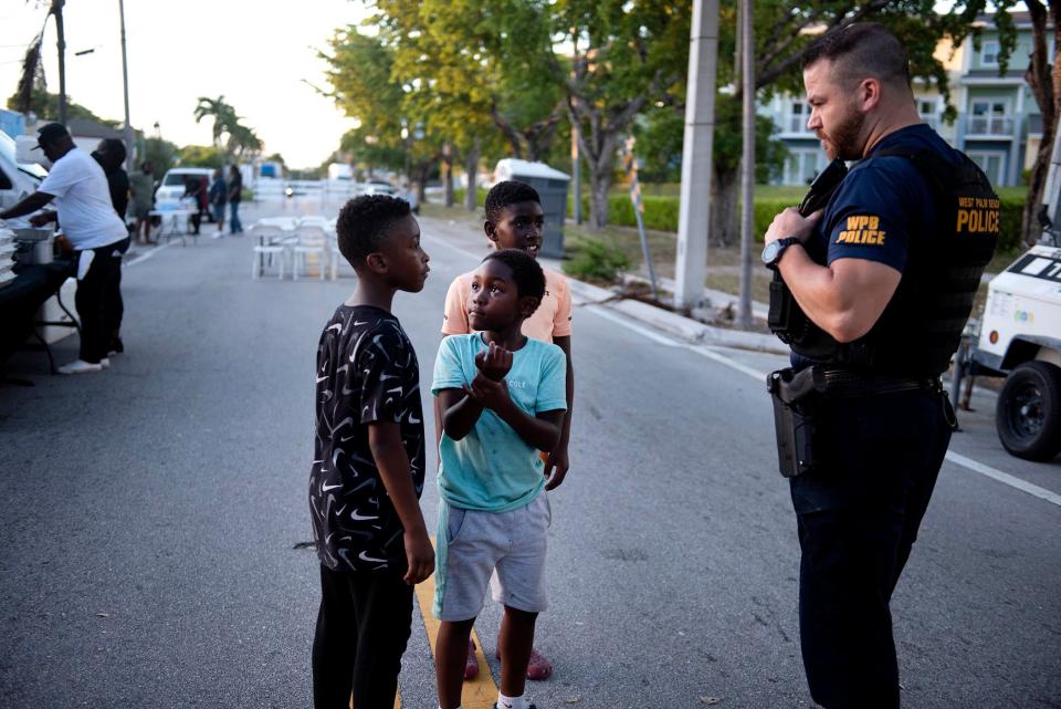 West Palm Beach Police Sgt. James Flaton answers questions from children during the PUSH (Pray Until Something Happens) to Curb Gun Violence block party on Tamarind Avenue in West Palm Beach on Friday night.
