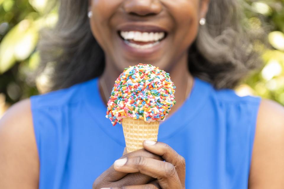 mature woman holding ice cream cone with sprinkles