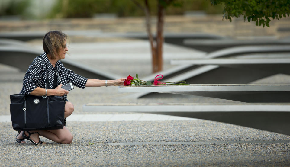 A woman reaches out to touch rose on one of the benches of the Pentagon Memorial at the at the Pentagon, Thursday, Sept. 11, 2014. President Barack Obama will attend the  wreath laying later this morning to to mark the 13th anniversary of the 9/11 attacks. (AP Photo/Pablo Martinez Monsivais)