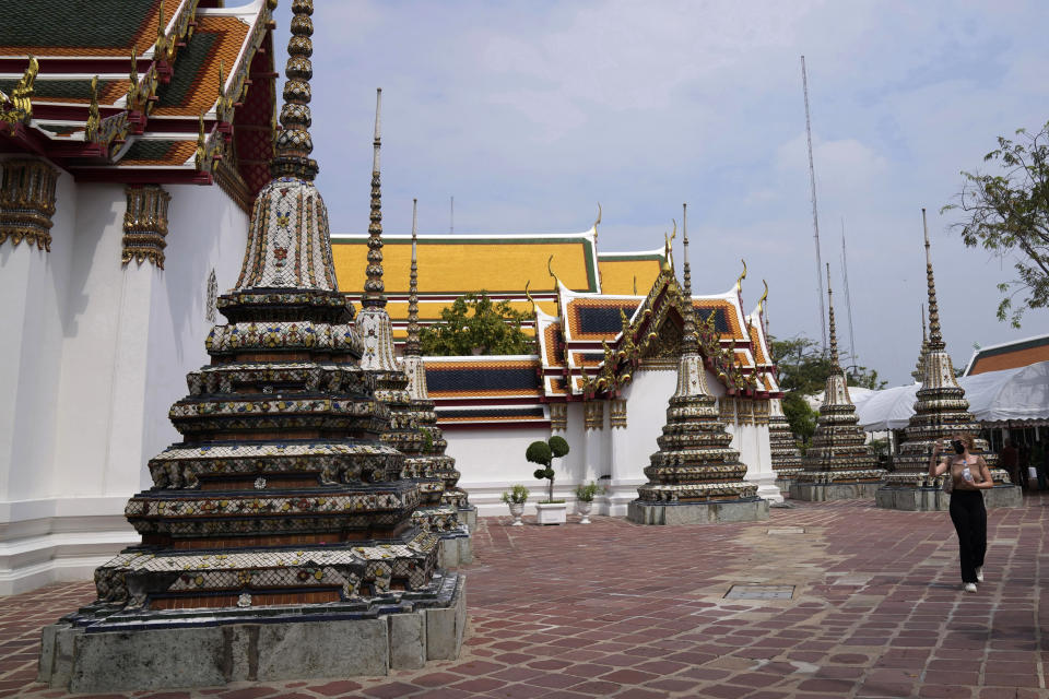 A tourist wearing protective masks tours at Wat Pho temple in Bangkok, Thailand, Wednesday, Feb. 23, 2022. Thailand will ease some entry requirements for foreign visitors as it balances a rising number of coronavirus cases with the need to rebuild its pandemic-damaged economy, the government announced Wednesday.(AP Photo/Sakchai Lalit)