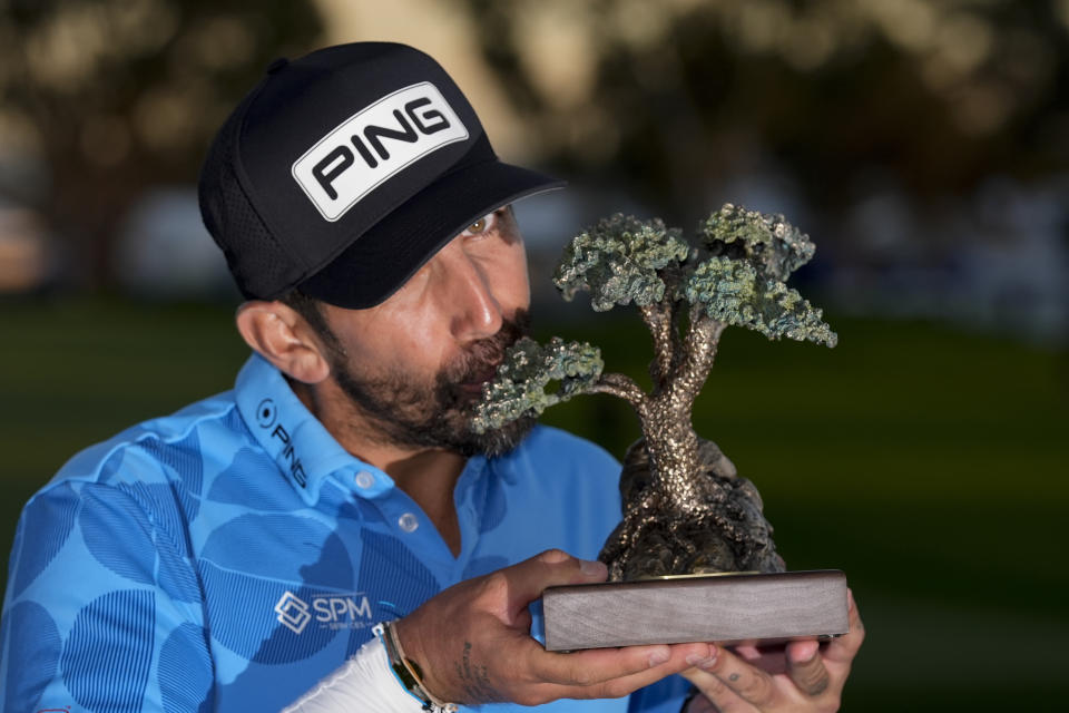 Matthieu Pavon kisses the trophy after winning the Farmers Insurance Open golf tournament, Saturday, Jan. 27, 2024, in San Diego. (AP Photo/Gregory Bull)