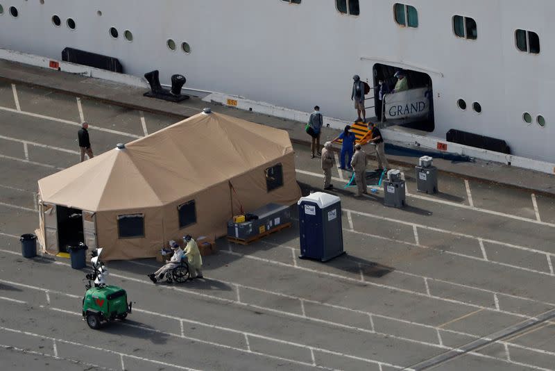 People in masks prepare to disembark the cruise ship Grand Princess as it docks at the Port of Oakland where tests for coronavirus (COVID-19) are being conducted and arrangements are being made to offload passengers in Oakland