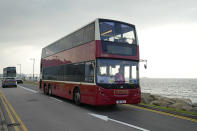 A double-decker bus passes on a waterfront road near airport in Hong Kong, Saturday, Oct. 16, 2021. Travel-starved, sleep-deprived residents might find a new Hong Kong bus tour to be a snooze. The 47-mile, five-hour ride on a double-decker bus around the territory is meant to appeal to people who are easily lulled asleep by long rides. (AP Photo/Kin Cheung)