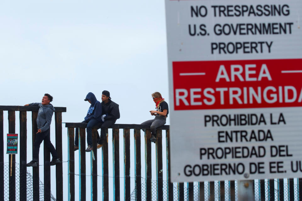 <p>People in Mexico climb the border wall fence as a caravan of migrants and supporters reached the United States-Mexico border near San Diego, California, April 29, 2018. (Photo: Mike Blake/Reuters) </p>