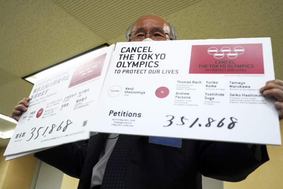 Lawyer Kenji Utsunomiya, a representative of an anti-Olympics group, holds boards showing the current figure of online petition during a press conference after submitting a petition to the Tokyo government calling for the cancellation of the Tokyo 2020 Olympics and Paralympics. An online petition calling for the Tokyo Olympics to be cancelled has been submitted to the Tokyo government with over 350,000 signatures on Friday morning. The rollout of the petition comes with Tokyo, Osaka and several other areas under a state of emergency with coronavirus infections rising - particularly new variants. (AP Photo/Eugene Hoshiko)