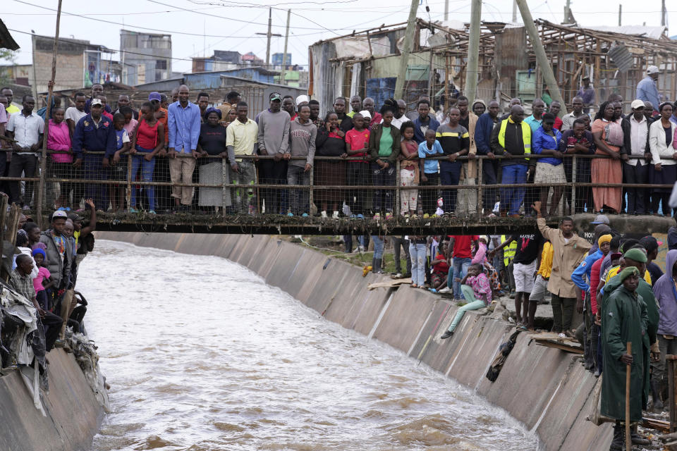 People stand on a bridge, as they watch houses in riparian land being demolished in the Mukuru area of Nairobi, Tuesday, May. 7, 2024. The government ordered the demolition of structures and buildings, illegally constructed along riparian areas. Kenya, along with other parts of East Africa, has been overwhelmed by flooding. (AP Photo/Brian Inganga)