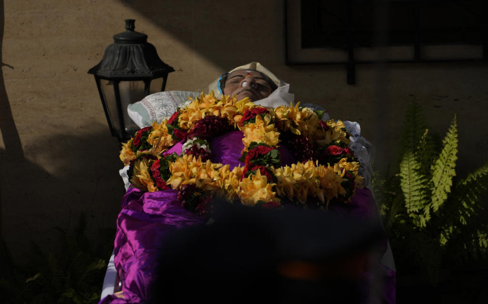 The body of Lata Mangeshkar, lies as people pay tribute outside her home in Mumbai, India, Sunday, Feb.6, 2022. The legendary Indian singer with a prolific, groundbreaking catalog and a voice recognized by a billion people in South Asia, died Sunday morning of multiple organ failure. She was 92. (AP Photo/Rafiq Maqbool)