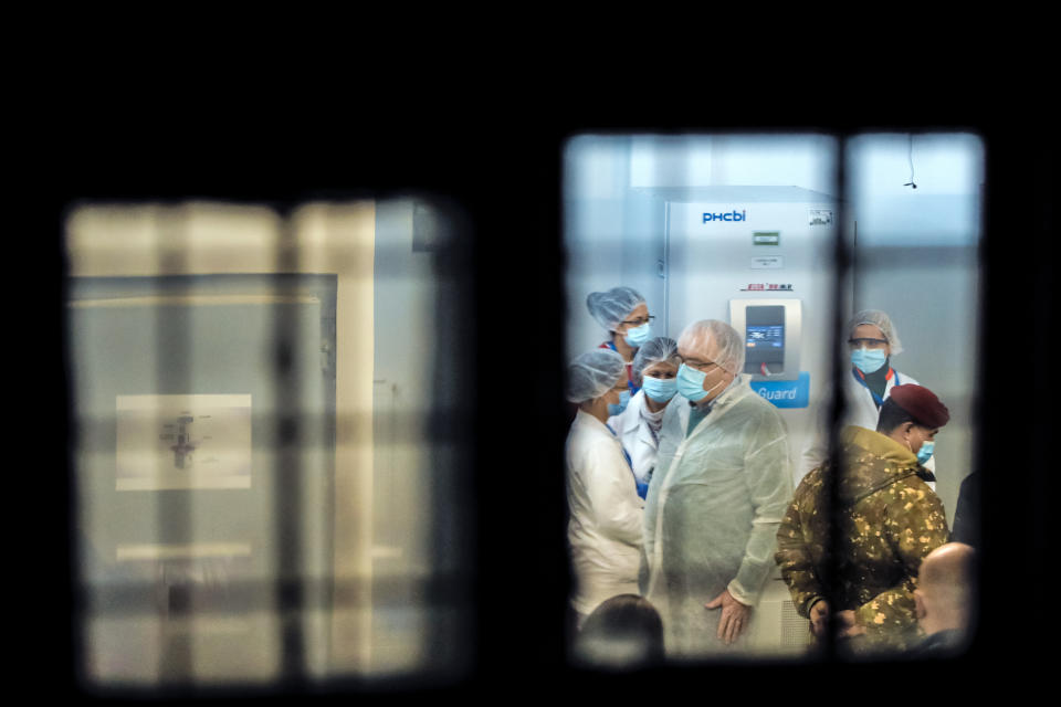 In this photo taken on Saturday, Dec. 26, 2020 medical staff and military personnel, wearing masks to protect against coronavirus, wait in the refrigerators room for the arrival of the first batch of COVID-19 vaccines at the National Center for Storage of the COVID-19 Vaccine, a military run facility, in Bucharest, Romania. Across the Balkans and the rest of the nations in the southeastern corner of Europe, a vaccination campaign against the coronavirus is overshadowed by heated political debates or conspiracy theories that threaten to thwart the process. In countries like the Czech Republic, Serbia, Bosnia, Romania and Bulgaria, skeptics have ranged from former presidents to top athletes and doctors. Nations that once routinely went through mass inoculations under Communist leaders are deeply split over whether to take the vaccines at all. (AP Photo/Vadim Ghirda)