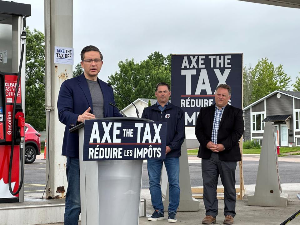 Federal Conservative Leader Pierre Poilievre stands in front of several 'Axe the Tax' signs at a press conference in New Brunswick in June 2023.  (Shane Magee/CBC - image credit)