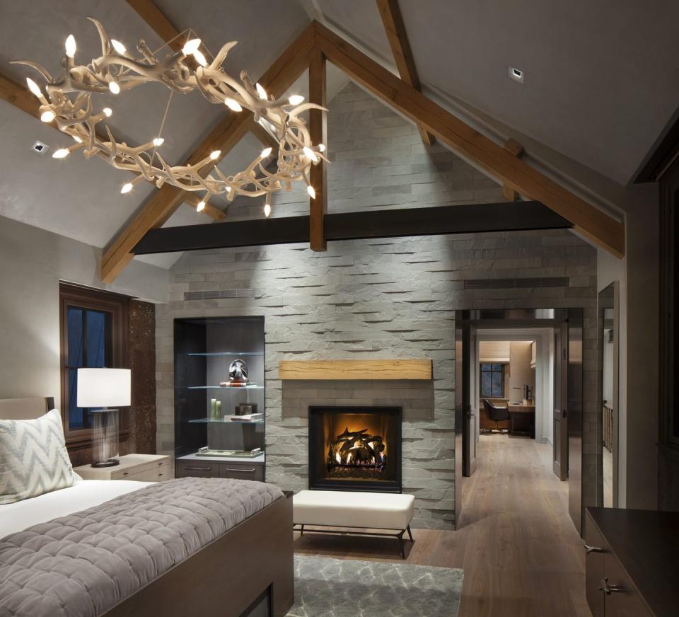 <p>From the circular chandelier to the stone accent wall, this bedroom is full of country elements. Design by <a href="https://deringhall.com/interior-designers/lkid" rel="nofollow noopener" target="_blank" data-ylk="slk:LKID;elm:context_link;itc:0;sec:content-canvas" class="link ">LKID</a>.</p>