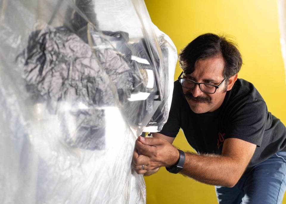 Aguila covers the robot with a sheet to protect it from water during a demonstration of how the robot works. Lauren Witte/lwitte@miamiherald.com