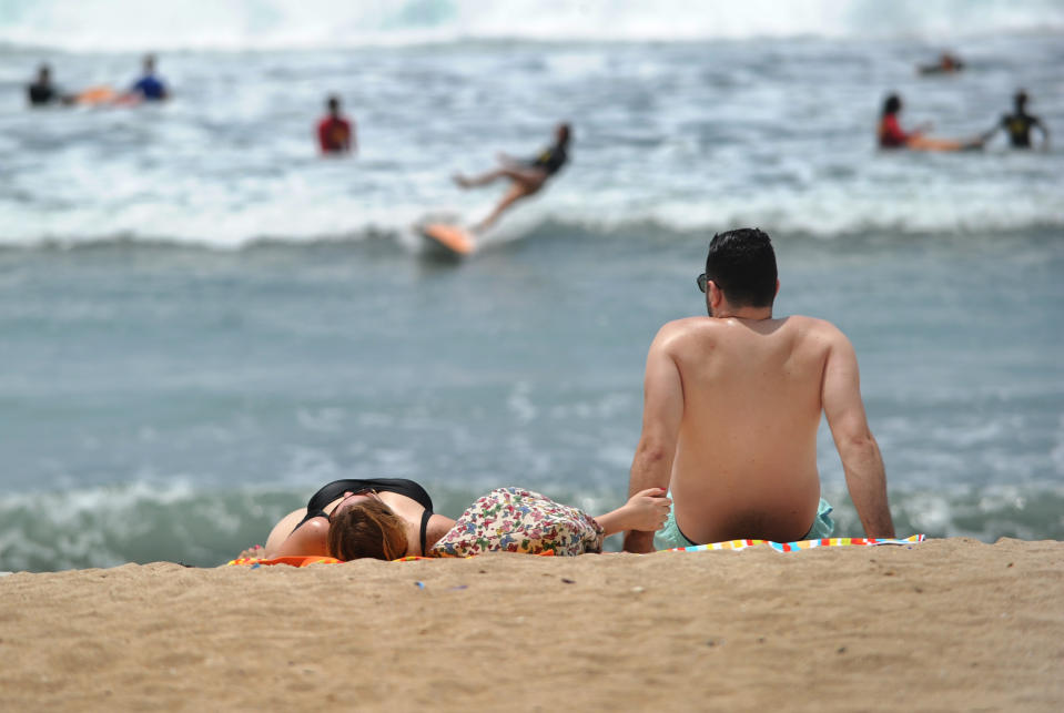 Tourists relax on Kuta beach on Indonesia's tourism island of Bali on January 4, 2019. (Photo by SONNY TUMBELAKA / AFP)        (Photo credit should read SONNY TUMBELAKA/AFP/Getty Images)