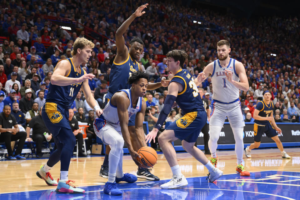 Kansas City guard Anderson Kopp (11), forward Jeff Ngandu, rear, and guard Cameron Faas (30) try to trap Kansas guard Elmarko Jackson, center, during the first half of an NCAA college basketball game in Lawrence, Kan., Tuesday, Dec. 5, 2023. (AP Photo/Reed Hoffmann)