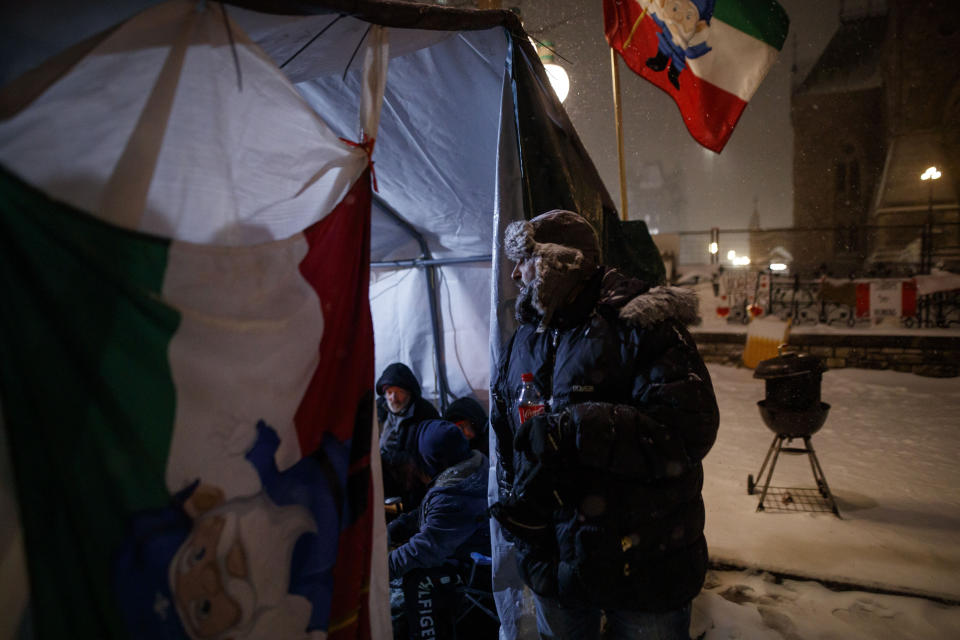 A man peers inside a tent as people gather during a protest against COVID-19 measures that has grown into a broader anti-government protest that continues to occupy downtown Ottawa, Ontario, on Thursday, Feb. 17, 2022. (Cole Burston/The Canadian Press via AP)