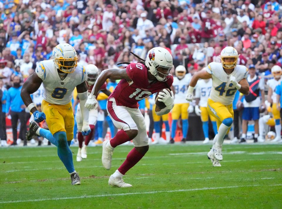 Nov 27, 2022; Glendale, AZ, USA;  Nov 27, 2022; Glendale, AZ, USA;  Arizona Cardinals wide receiver DeAndre Hopkins (10) runs away from Los Angeles Chargers linebackers Kenneth Murray Jr. (9) and Troy Reeder (42) before scoring a touchdown after a catch during the first quarter at State Farm Stadium.