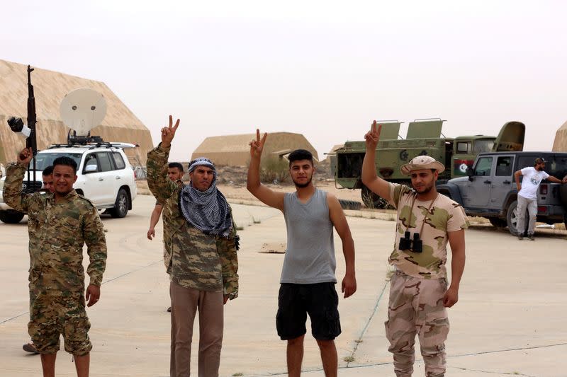 Members of Libya's internationally recognised government flash victory signs after taking control of Watiya air base