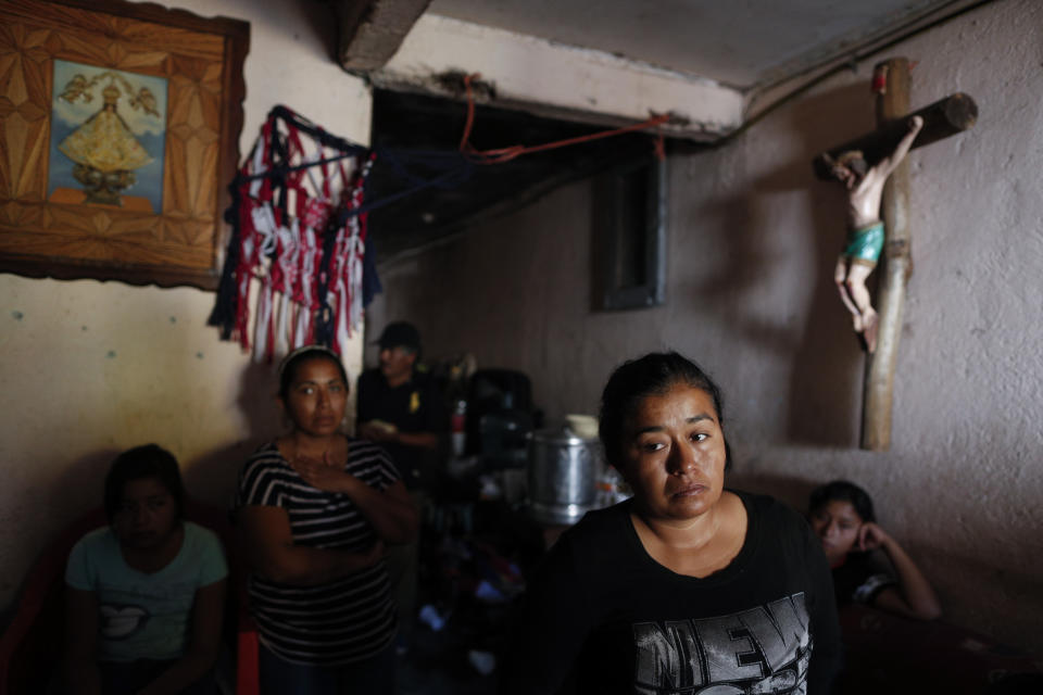 In this Feb. 13, 2020 photo, Maria Guadalupe Gallardo Lopez stands with other family members as they mourn her husband Juan Carlos Medina Serrano, in the family's living room, the day his remains were buried, more than two months after armed men pulled him from his home, in Irapuato, Guanajuato state, Mexico. While families like Gallardo López's suffer, many in Guanajuato live lives largely untouched by the violence. (AP Photo/Rebecca Blackwell)