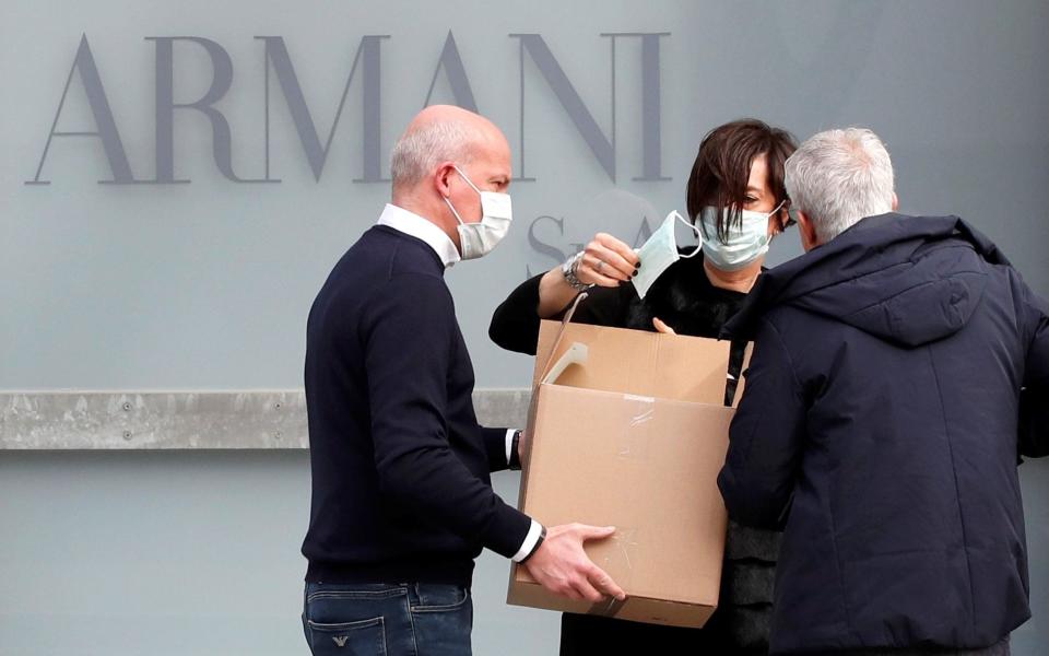 A worker holds a face mask outside the theatre where the Italian designer Giorgio Armani said his Milan Fashion Week show would take place in Milan - REUTERS