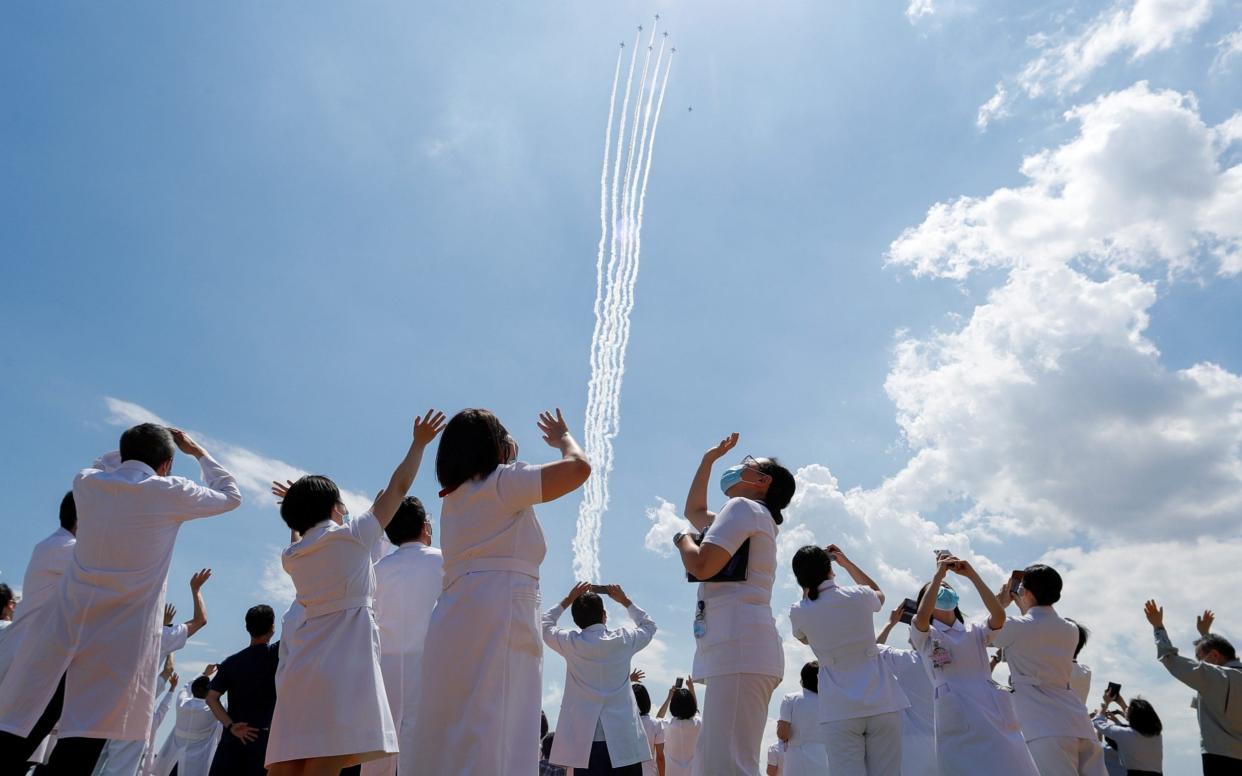  Medical workers react as they watch the 'Blue-Impulse' aerobatic team of Japan Air Self-Defense Force as they fly over the Self-Defense Forces Central Hospital to salute the medical workers at the frontline of the fight against the coronavirus disease (COVID-19) in Tokyo, Japan - Reuters