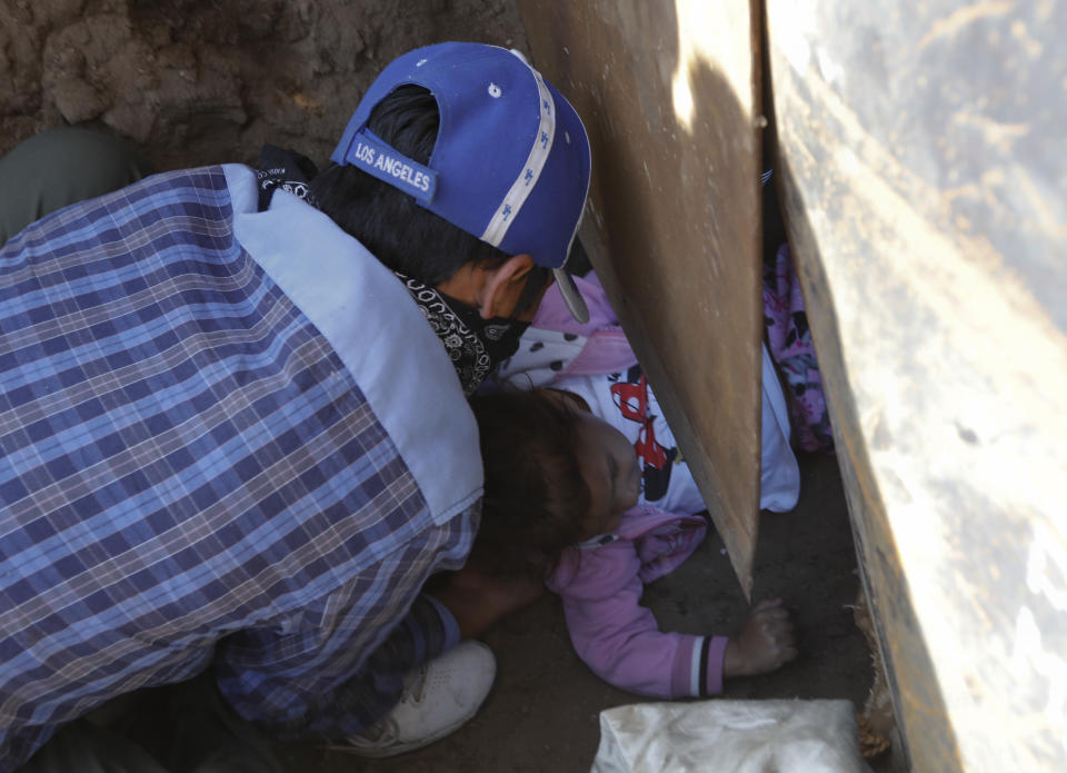 La hondureña Charlot Andrea, de 3 años, es empujada debajo de una cerca fronteriza de Estados Unidos desde el lado de Tijuana, México, para reunirse con su madre Rachel Rivera, de 19 años, en territorio estadounidense, el jueves 4 de diciembre de 2018. (AP Foto/Rebecca Blackwell)