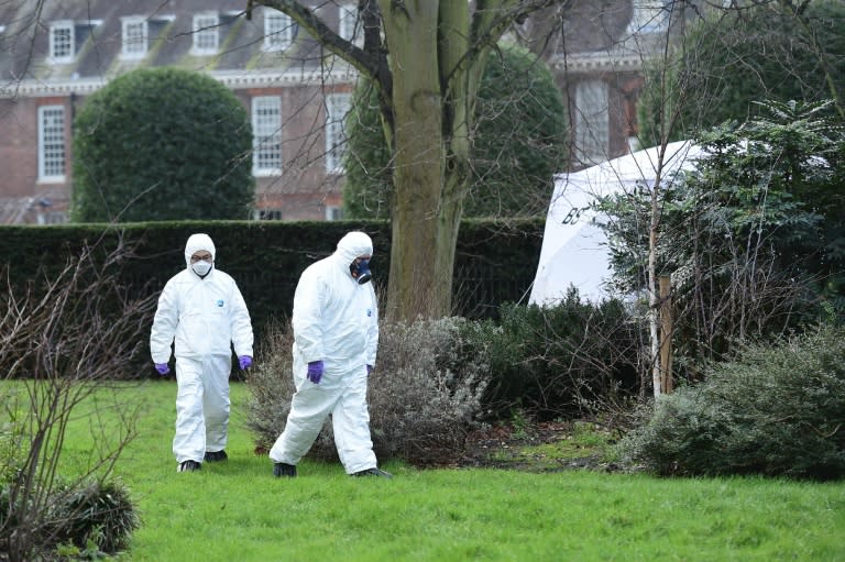 Forensics officers in overalls and masks walk past a tent erected over the spot where a man died after being discovered on fire in the park outside the wall of Kensington Palace, central London on February 9, 2016