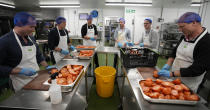 Volunteers from the charity 'The Felix Project' prepare meals in the kitchen of their hub in London, Wednesday, May 4, 2022. Across Britain, food banks and community food hubs that helped struggling families, older people and the homeless during the pandemic are now seeing soaring demand. The cost of food and fuel in the U.K. has risen sharply since late last year, with inflation reaching the highest level in 40 years. (AP Photo/Frank Augstein)