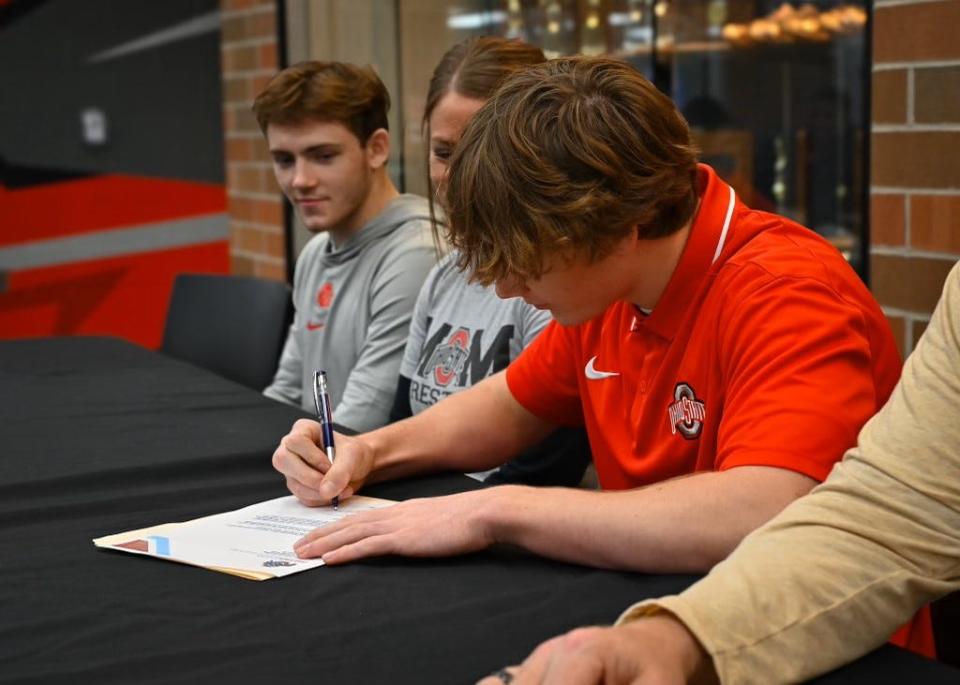 Pleasant senior Daxton Chase sings his letter of intent to wrestle at Ohio State next season while flanked by family members during last week's signing at the high school.