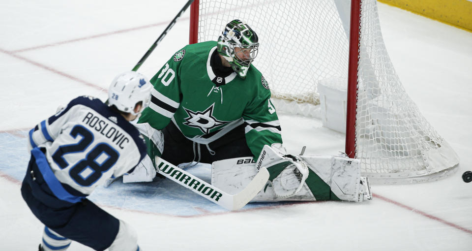 Dallas Stars goaltender Ben Bishop (30) deflects a shot from Winnipeg Jets forward Jack Roslovic (28) during the first period an NHL hockey game Thursday, Dec. 5, 2019, in Dallas. Dallas won 3-2 in overtime. (AP Photo/Brandon Wade)