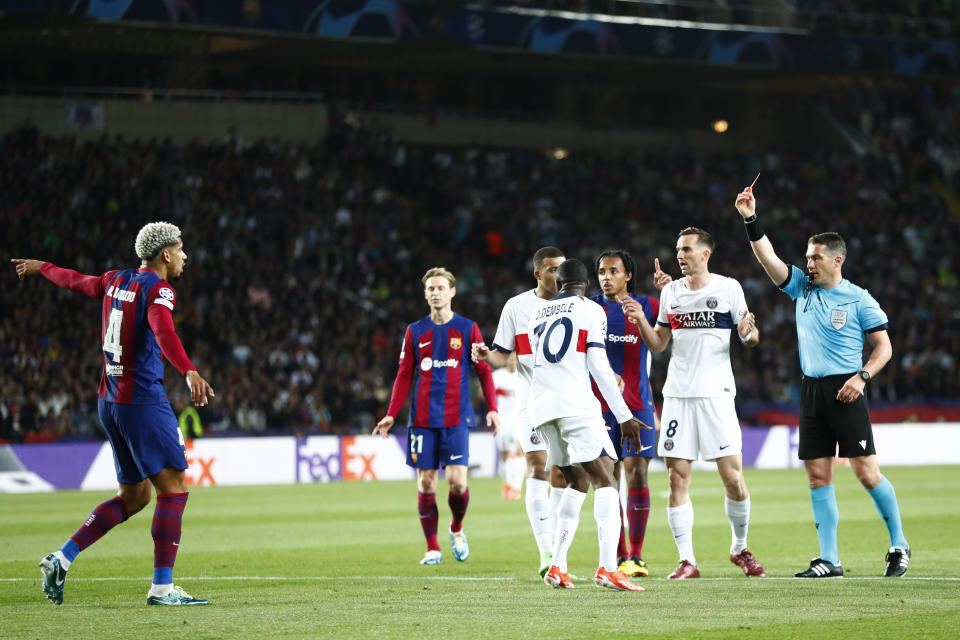 Barcelona's Ronald Araujo, left, gets a red card by referee Istvan Kovacs during the Champions League quarterfinal second leg soccer match between Barcelona and Paris Saint-Germain at the Olimpic Lluis Companys stadium in Barcelona, Spain, Tuesday, April 16, 2024. (AP Photo/Joan Monfort)